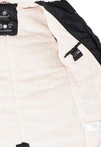 Black outer shell jacket with a soft, light beige fleece lining. Features interior pockets and brand labels. Zipper and buttons are present.