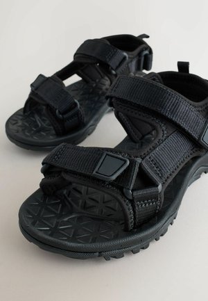 Sandale negre cu barete reglabile din nylon texturat, cu talpă de cauciuc care prezintă un model de diamant pentru aderență.