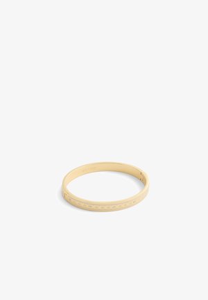 La pulsera bangle de color dorado presenta una superficie lisa con patrones troquelados y piedras de imitación incrustadas, creando un diseño contemporáneo.