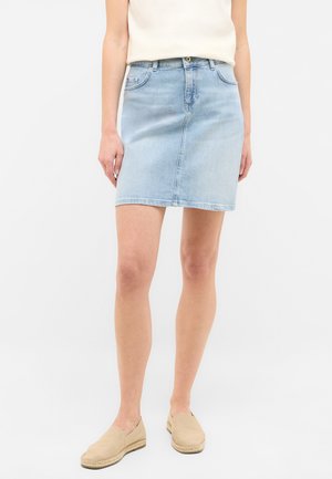 Light blue denim skirt with a straight fit, mid-thigh length, front pockets, and a button closure. Worn with beige slip-on shoes.