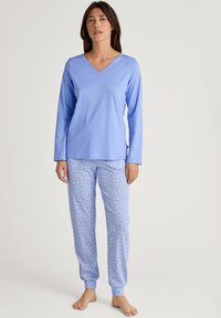 Lichtblauw, lang mouwen V-hals top, gecombineerd met gestreepte blauwe pyjamabroek met een bloemenpatroon en manchetten rond de enkels. Zachte stof.