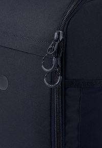 Schwarzer Stoff-Rucksack mit einem robusten Reißverschluss mit doppeltem Zipper, strukturiertem Seitenpanel und einem runden Logopatch.
