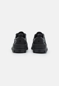 Zapatillas negras con una suela de goma texturizada, parte superior de tela suave y un distintivo logo de estrella en la parte trasera. Punta redondeada y cuello acolchado.
