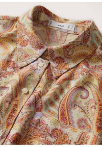 Chemise boutonnée à col avec un motif cachemire complexe dans des tons d'orange, de rose, de jaune et de bleu clair sur un fond beige.