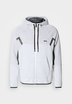 Light gray zip-up hoodie made of textured fabric, featuring a hood, black accents, and a logo on the left chest.