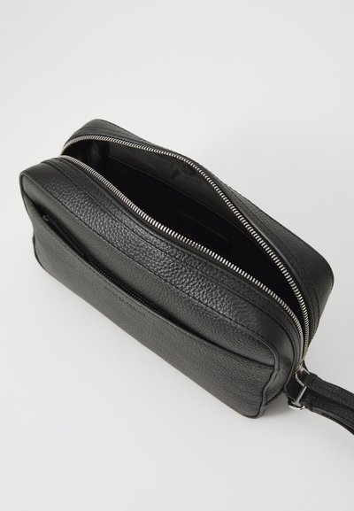 Geantă crossbody din piele neagră cu finisaj texturat, având un fermoar argintiu și un singur buzunar exterior. Interiorul este căptușit cu material textil.