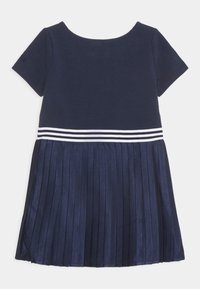 Námořnická modrá šaty s krátkým rukávem a skládáním sukně, s bílým pruhovaným designem v pase a hladkou horní částí.