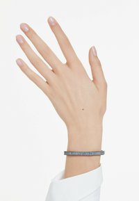 Pulsera de metal con acentos rectangulares azules, que presenta un diseño elegante y un cierre cerrado. Lleva puesta en una mano con esmalte claro.