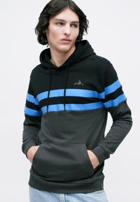Sweatshirt com capuz em preto e cinza, com riscas horizontais azuis, bolso canguru e logo de montanha subtil no peito. Textura de tecido suave.