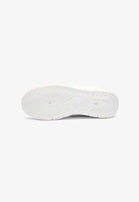 Sola de sneaker branca com borracha texturizada para tração, apresentando padrões circulares e lineares, design robusto e um acabamento suave.