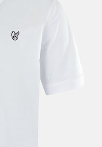 Polo bianca a maniche corte, con un logo ricamato nero sul lato sinistro del petto e un design del colletto classico. Tessuto morbido.