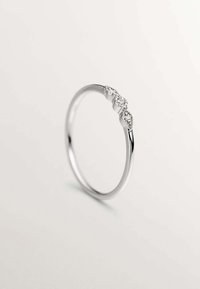 Anillo de plata con una banda lisa y tres acentos de piedras preciosas transparentes agrupadas en la parte superior, con un acabado pulido y un diseño elegante.