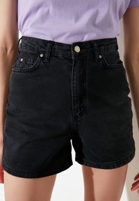 Pantalones cortos de mezclilla negros de cintura alta, con diseño de cinco bolsillos y herrajes plateados. Presentan una textura suave y un corte recto.