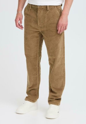 Brown corduroy pants with a ribbed texture, featuring a straight-leg design and front pockets, paired with white sneakers.