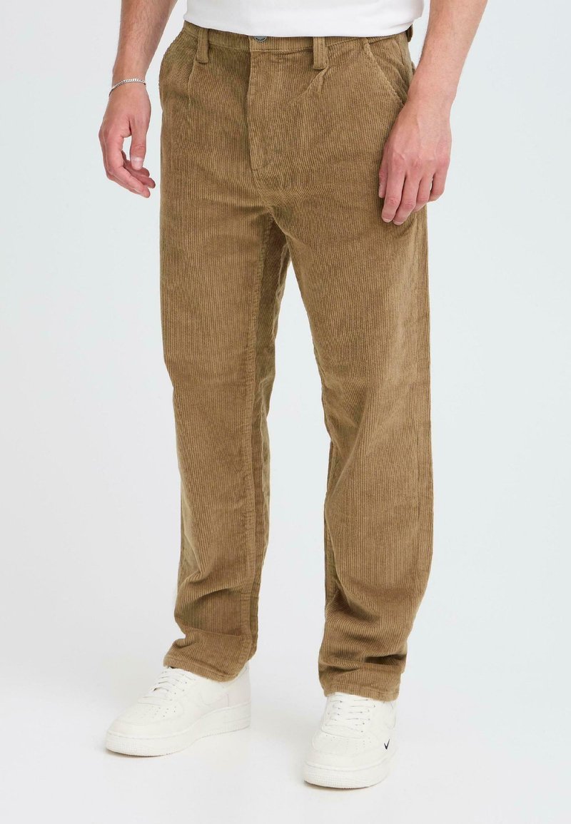 Brown corduroy pants with a ribbed texture, featuring a straight-leg design and front pockets, paired with white sneakers.