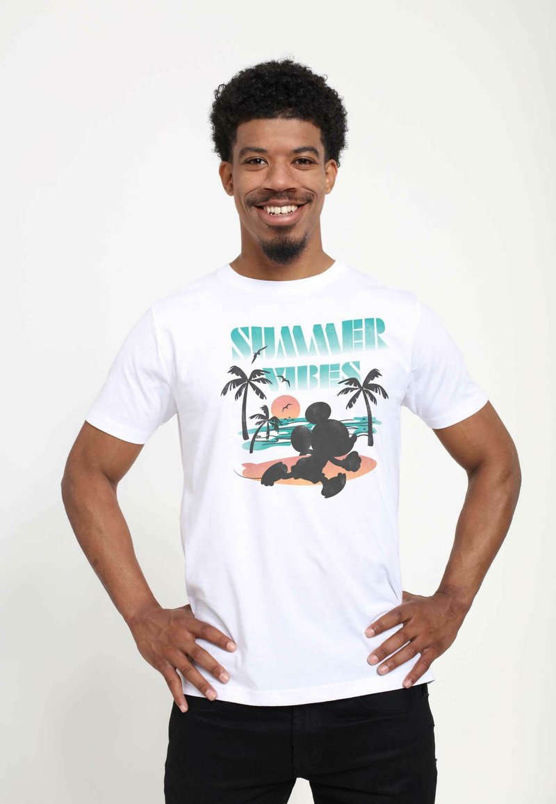 Weißes Baumwoll-T-Shirt mit dem Text "SUMMER VIBES" und einem Grafikmotiv eines Charakters am Strand mit Palmen und einem Sonnenuntergang.