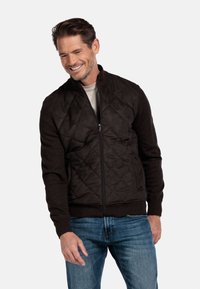 Gevulde bruine jack met een ritssluiting aan de voorkant, voorzien van effen bruine mouwen, geribbelde manchetten en een licht ontwerp. Draag het over een licht shirt.