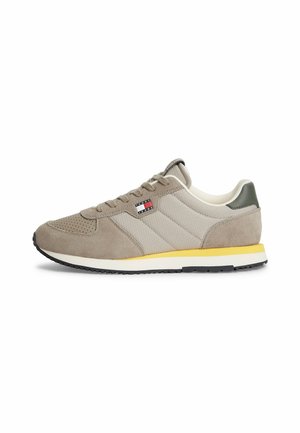 Casual beige sneaker med ruskind og stofpaneler, gul midtersålstribe, sort ydersål og lille Tommy Jeans flaglogo på siden.