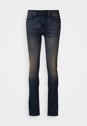 Dark blue slim-fit jeans with faded areas on thighs and knees, featuring front pockets and button closure.