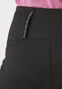 Černá sportovní sukně z hladkého, elastického materiálu. Obsahuje boční štítek s textem "ZDRAVÁ MYSL, ZDRAVÉ TĚLO" a jemné švy.