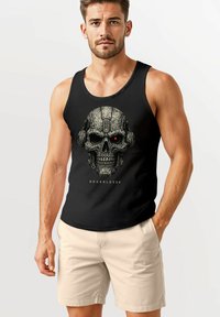 Black tank top featuring a skull design with mechanical details and a red accent eye. Worn with light beige shorts.