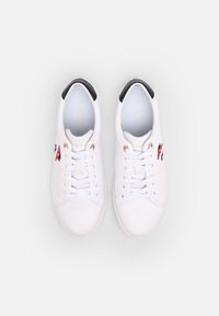 Pair of white low-top sneakers with white laces, black heel detail, and red, white, and blue logo embroidery on the side.