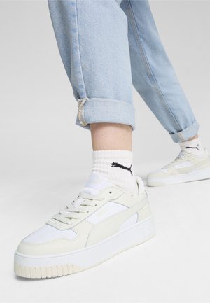 Sneakers bianche con suola spessa, tomaia in pelle liscia e cuciture tonali. Indossate con jeans azzurri arrotolati e calzini bianchi a costine con logo.