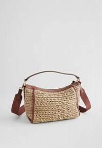 Sac en paille tissée beige avec une bandoulière en simili cuir marron. Dispose d'une fermeture éclair et de bords renforcés. Forme compacte et arrondie.
