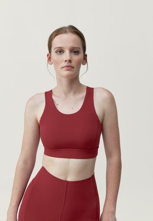 Rode sportcrop top met een ronde halslijn en brede bandjes. Gemaakt van soepel, rekbaar materiaal. Gecombineerd met bijpassende high-waisted leggings.