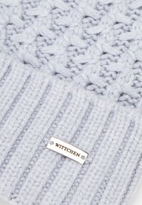 Lichtblauwe gebreide beanie met een gestructureerd kabelpatroon, voorzien van een geribde boord en een metalen label met de gravure "Wittchen".