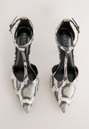 Spidse tåsko med hæl i et mønster, der ligner slangeskind, med sort-hvid farveskema, ankelrem og åbne sider for bedre åndbarhed.