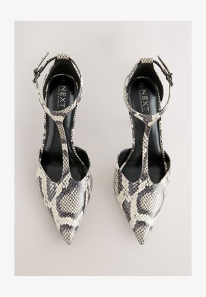 Árkádorrú magassarkúk mű kígyóbőr mintával, fekete-fehér színkombinációval, bokapánttal és nyitott oldalakkal a szellőzés érdekében.