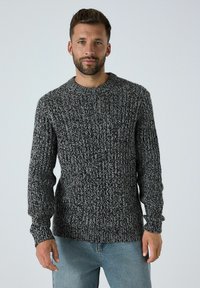 Pulover gri cu fire ribbate, cu un finisaj texturat, guler rotund și mâneci lungi, asociat cu blugi din denim de culoare albastră deschisă.