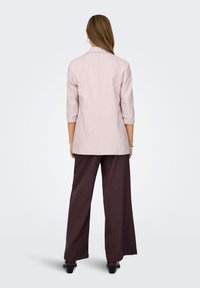 Ροζ σακάκι με τρία τέταρτα μανίκια, λεπτομέρεια ραφής στην πλάτη, σετ με καφέ παντελόνες με φαρδιά πόδια, με ομαλή υφή υφάσματος.