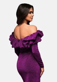 Violetti mekko, jossa on suuret röyhelöillä varustetut olkaimeton kaula-aukko ja pitkät hihat. Struktuurinen kangas, jossa on tiukka siluetti.