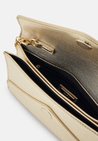 Pochette en simili cuir doré avec un intérieur métallique, comprenant une poche zippée et deux compartiments. Inclut une fermeture à chaîne et à pression.