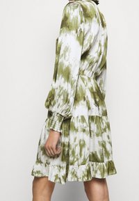 Groene en witte tie-dye jurk met lange gepofte mouwen, ruffled zoom en elastische manchetten, met een cinch taille en gelaagd ontwerp.