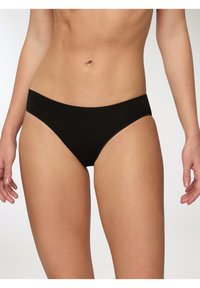 Slip bikini neri in cotone con una texture liscia, design a vita bassa e minimal dettagli di cucitura. Adatti per un uso quotidiano.