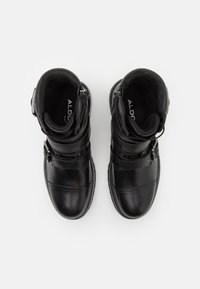 Botas de cuero negro hasta el tobillo con un acabado suave, interior acolchado, dos correas y cremallera discreta en el lateral.