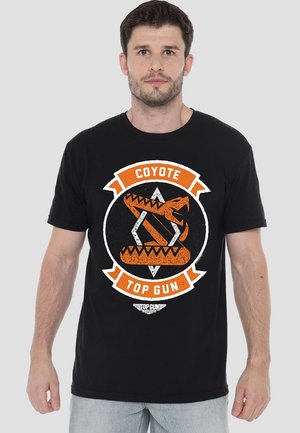 Black cotton t-shirt featuring a circular, distressed graphic in orange and white, displaying a coyote with text “COYOTE” and “TOP GUN.”