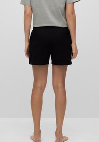 Svarta bomullsshorts med en enkel design, som har resårmidja, längd till mitten av låret och en slät yta. Inga märkbara detaljer.