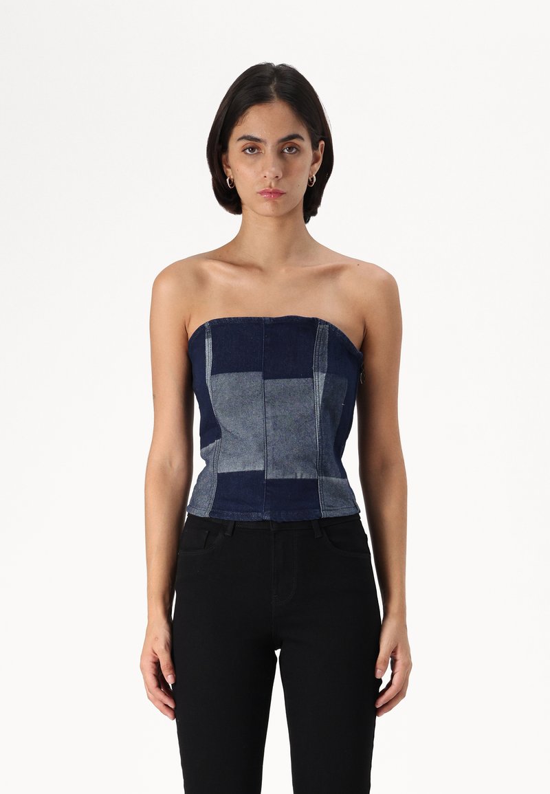 Top din denim fără bretele, cu un design patchwork în nuanțe de albastru închis și deschis, cu cusături structurale și o siluetă ajustată.