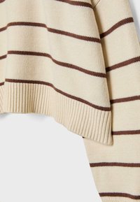 Pull beige en maille avec des rayures horizontales brun foncé, ourlet côtelé et coupe décontractée. La texture semble douce et légèrement duveteuse.
