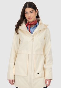 Beige wasserdichte Jacke mit einem Frontreißverschluss, verstellbarem Kapuzen, und zwei großen Fronttaschen. Sie hat ein dezentes Logo und eine glatte Textur.