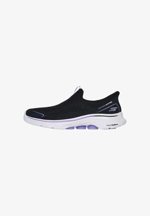 Zapatilla sin cordones negra con parte superior de punto texturizado, suela blanca y acentos morados, que incluye un tirador en el talón para facilitar su uso.
