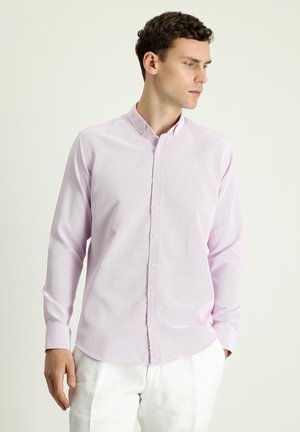 Camisa de botones de color rosa claro en tejido texturizado, con cuello, mangas largas y dobladillo recto. Los botones son pálidos y sutiles.