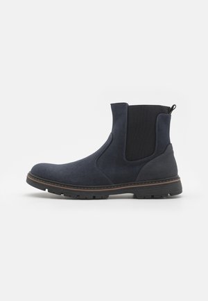 Navy blue suede Chelsea boot with black elastic side panels, brown welt stitching, and a thick black rubber sole with tread.
