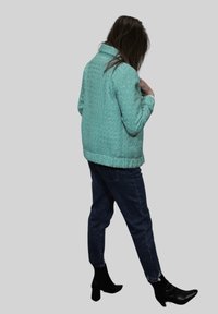 Chaqueta verde menta texturizada con cuello y mangas largas, combinada con vaqueros azul oscuro y botines negros de tacón.