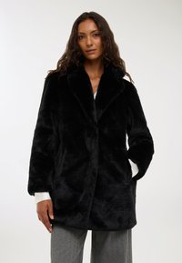 Czarny płaszcz z sztucznego futra z szerokim kołnierzem, d�ługimi rękawami i luźnym krojem. Posiada boczne kieszenie oraz miękką, puszystą teksturę.