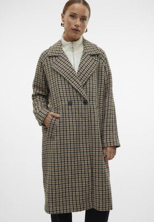 Brown and beige plaid coat with a double-breasted front, large lapels, patch pockets, and wide sleeves. Worn over a white high-neck top.